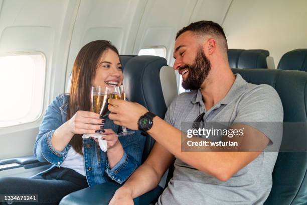 young couple flying and toasting. - couple airplane stockfoto's en -beelden