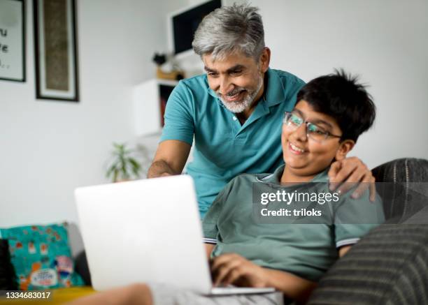 happy father and son using laptop at home - boy indian stockfoto's en -beelden