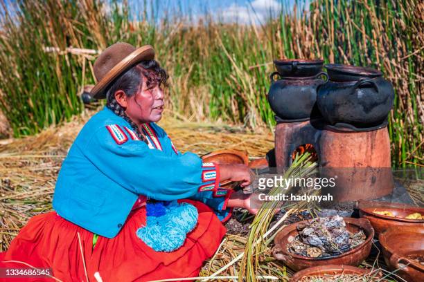peruvian woman cooking on uros floating island, lake tititcaca - uroseilanden stockfoto's en -beelden