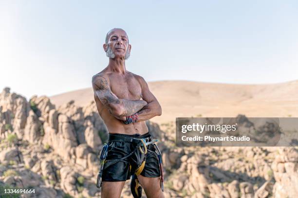 athletic mature man portrait before climbing on overhanging cliff rock - distinguished gentlemen with white hair stock pictures, royalty-free photos & images