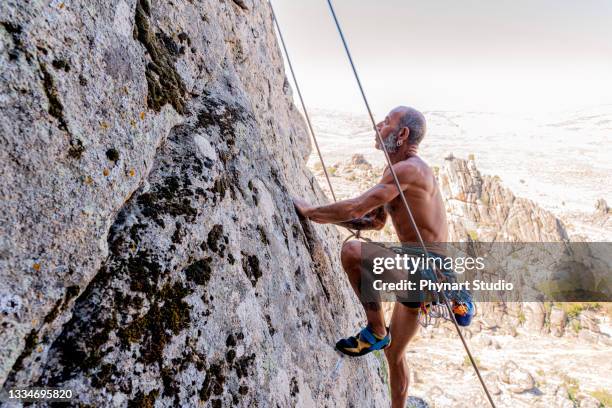 athletic old man climbing on overhanging cliff rock - distinguished gentlemen with white hair stock pictures, royalty-free photos & images