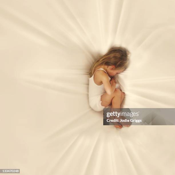 child laying on white sheet - bedclothes stock pictures, royalty-free photos & images