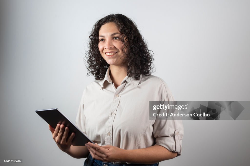 Mujer latina mayor de 30 años posando en estudio, con tablet