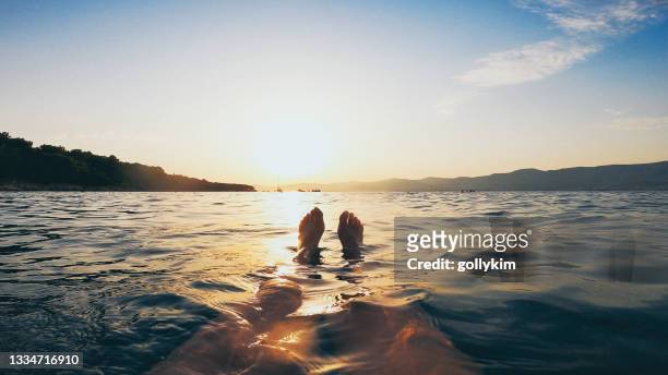 personal point of view of woman legs, swimming in the adriatic sea during sunset, split, croatia - kroatien strand stock pictures, royalty-free photos & images
