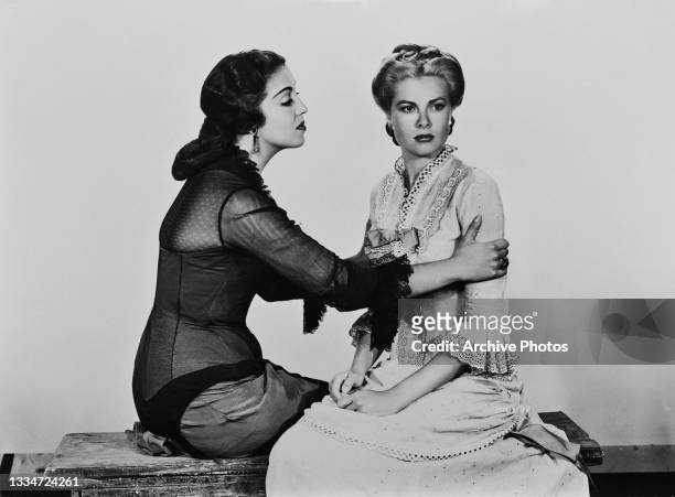 Mexican actress Katy Jurado consoling American actress Grace Kelly , who looks away, in a publicity image for 'High Noon, location unspecified, 1952....