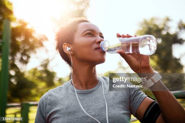 afroamerikanische joggerin, die morgens wasser trinkt - sport drinking bottle stock-fotos und bilder