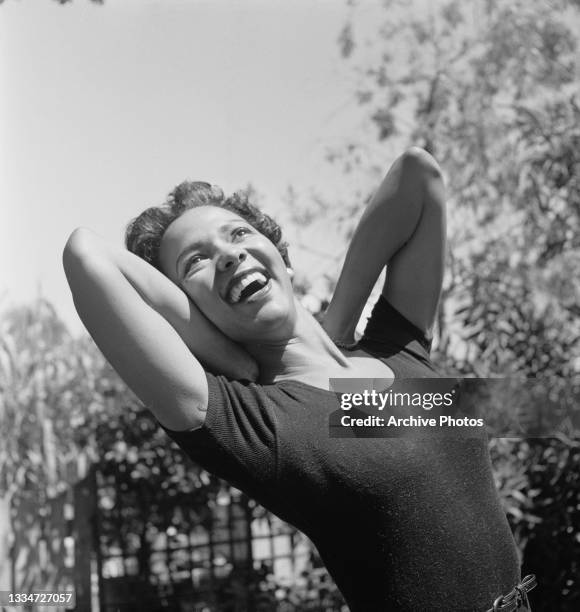 American actress, singer and dancer Dorothy Dandridge wearing a leotard as she stretches, both arms behind her neck, location unspecified, 22nd...