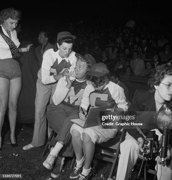 American actress Jane Russell speaking with unspecified celebrities wearing baseball kits at the 'Out of This World' Series charity baseball game in...