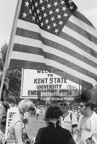 Protestor holds a placard that reads 'Welcome to Kent State University, enrollment 19,156' which has been crossed out and corrected to read '19,151'...