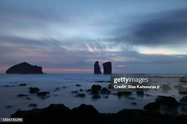 blue hour long exposure seascape, rocks and cliffs under blue sky with moving clouds - fogo photos et images de collection