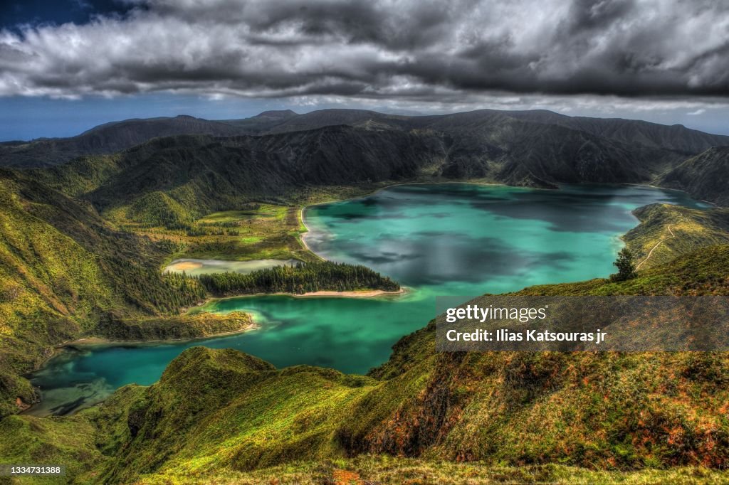 Lagoa do Fogo crater turquoise lake within massif stratovolcano under dramatic cloudy sky