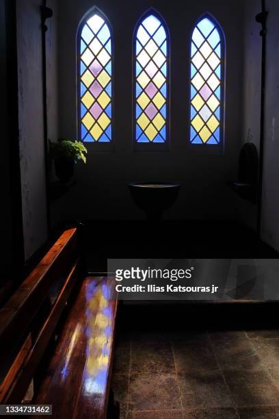 light entering from colorful stained glass window reflected on wooden church pew - entering church stock pictures, royalty-free photos & images