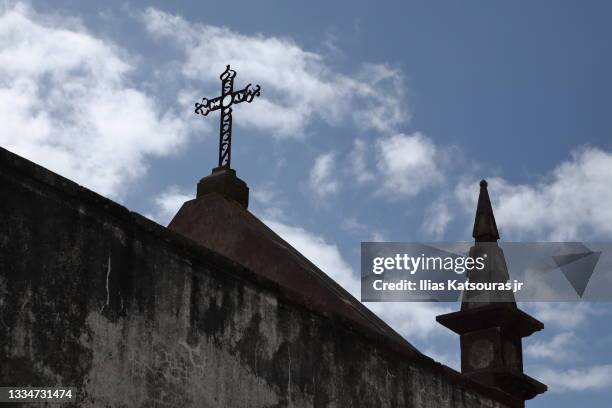 church spire and cross against blue cloudy sky, behind wall - catholicism fotografías e imágenes de stock