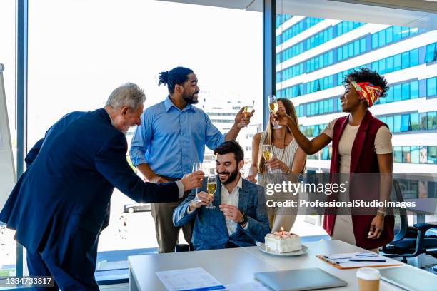 grupo de personas de negocios exitosas se divierten celebrando el cumpleaños de un colega y brindando con vino. - fiesta en la oficina fotografías e imágenes de stock