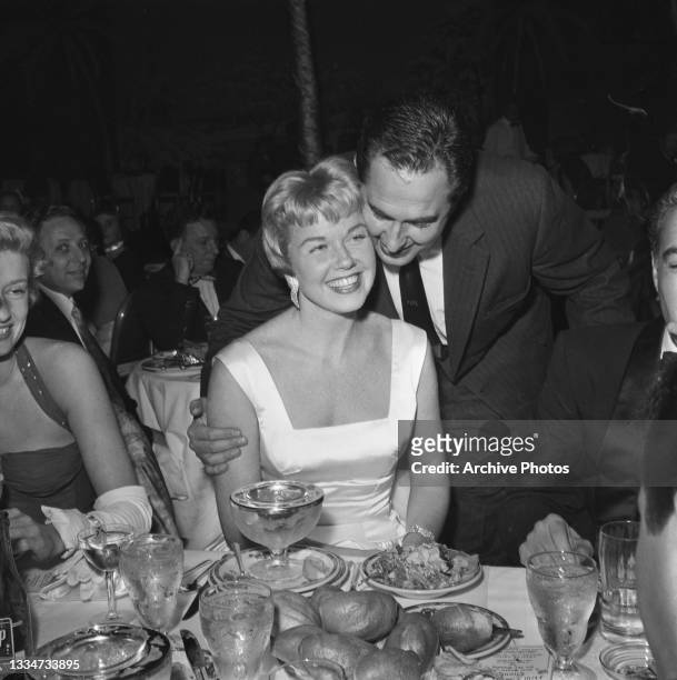 American actress and singer Doris Day , wearing a white outfit with a square neckline, with her husband, American film and music executive Martin...