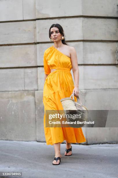 Ketevan Giorgadze @katie.one wears a one shoulder cut out maxi dress in orange from Mango, oversized golden hoop earrings from Zara, flip flop heeled...