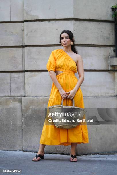 Ketevan Giorgadze @katie.one wears a one shoulder cut out maxi dress in orange from Mango, oversized golden hoop earrings from Zara, flip flop heeled...