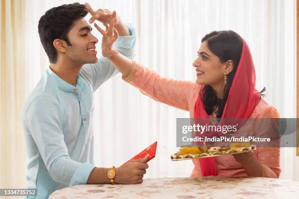 a happy brother and sister playfully following rituals on rakshabandhan - rakhi ストックフォトと画像