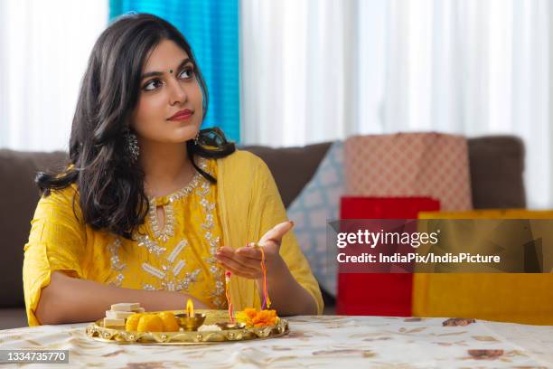 a young woman looking above while holding rakhi in hand - raksha bandhan fotografías e imágenes de stock