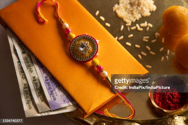 rakhi kept on an envelope with sweets and tika in a plate - rakhi stock pictures, royalty-free photos & images