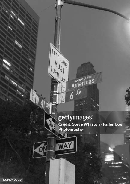 crowded streetlight post in manhattan with multiple road signs at night - street light post stock pictures, royalty-free photos & images