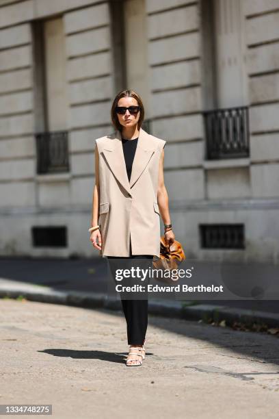 Julia Comil wears a transitional outfit for fall with a sleeveless beige cream blazer by Brigitte Herskind, a sleeveless black jumpsuit by Iro, white...