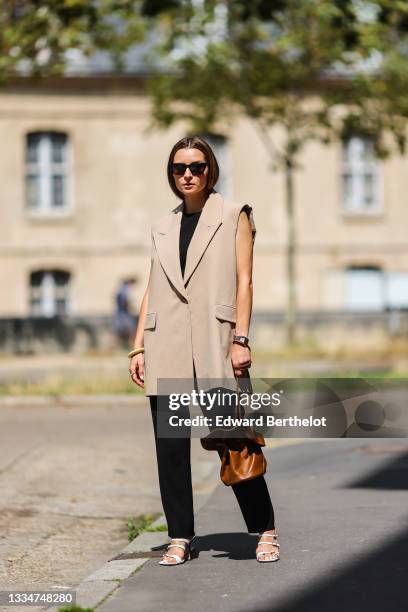 Julia Comil wears a transitional outfit for fall with a sleeveless beige cream blazer by Brigitte Herskind, a sleeveless black jumpsuit by Iro, white...