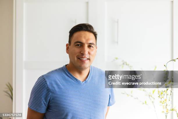 mid adult millennial male of colombian ethnicity standing near window looking at camera photo series - neckline stock pictures, royalty-free photos & images