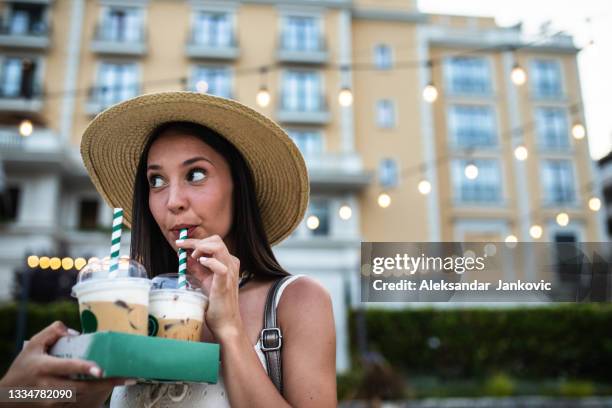 a pretty young woman drinking iced coffee through a straw - iced coffee stock pictures, royalty-free photos & images