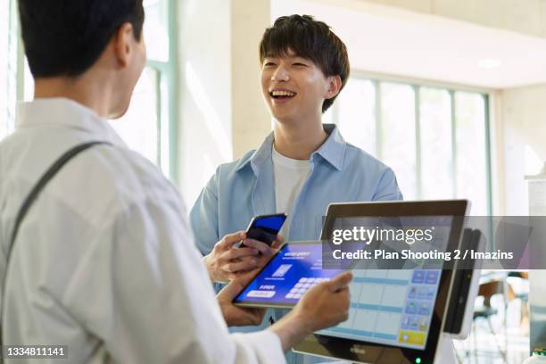 a customer trying to pay the bill with bitcoin - south korea bitcoin industry stock pictures, royalty-free photos & images