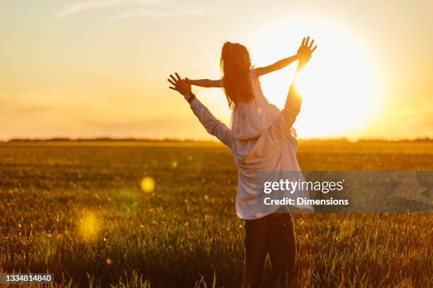 niña sobre los hombros de sus padres en los campos - father day fotografías e imágenes de stock