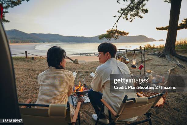 a couple roasting marshmallow by campfire - 韓国　スイーツ ストックフォトと画像