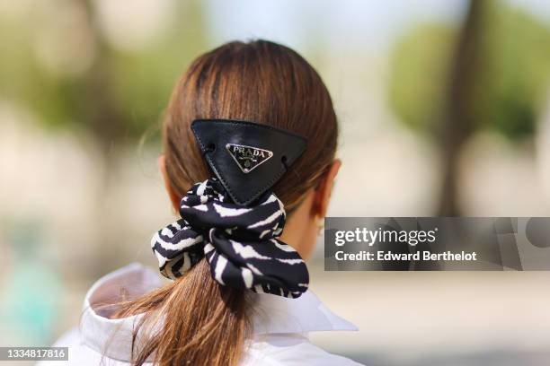 Julia Comil wears a Prada hair triangle barrette, a maxi scrunchie, on August 15, 2021 in Paris, France.