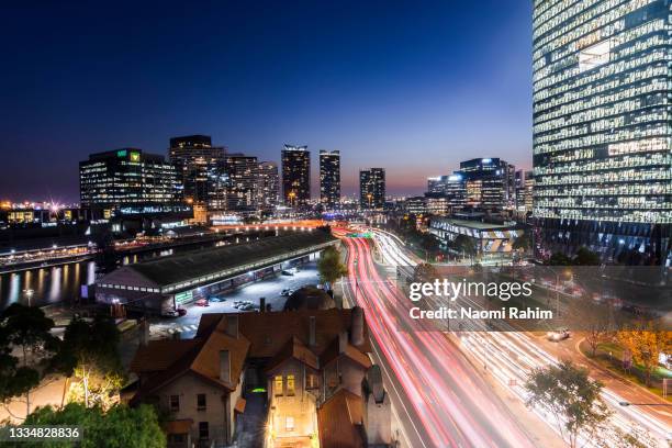 light trails through modern melbourne city skyline at night - melbourne lights stock pictures, royalty-free photos & images