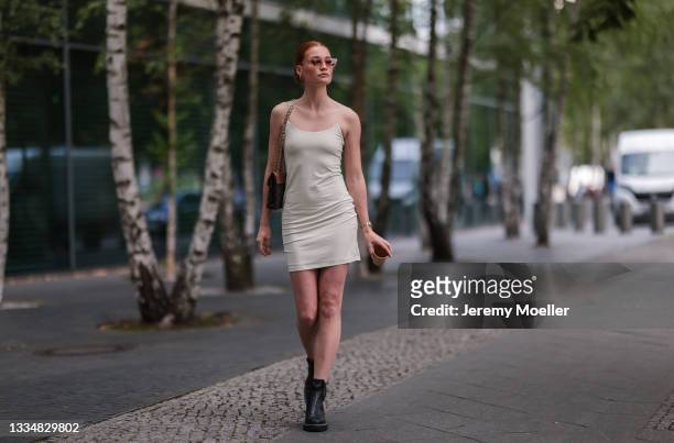 Jana Heinisch wearing LeGer beige mini dress, Louis Vuitton brown bag and black boots on August 12, 2021 in Cologne, Germany.