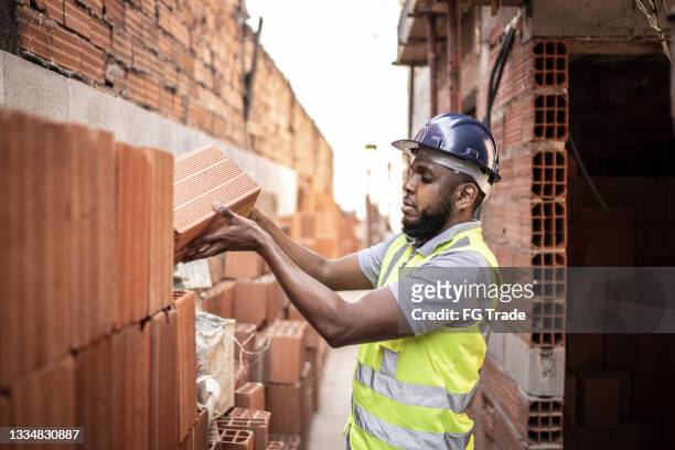 bauarbeiter baut eine ziegelmauer - brick layer stock-fotos und bilder