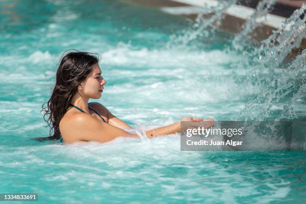 woman near of spa hydrotherapy waterfall jet in swimming pool - algar waterfall spain stock pictures, royalty-free photos & images