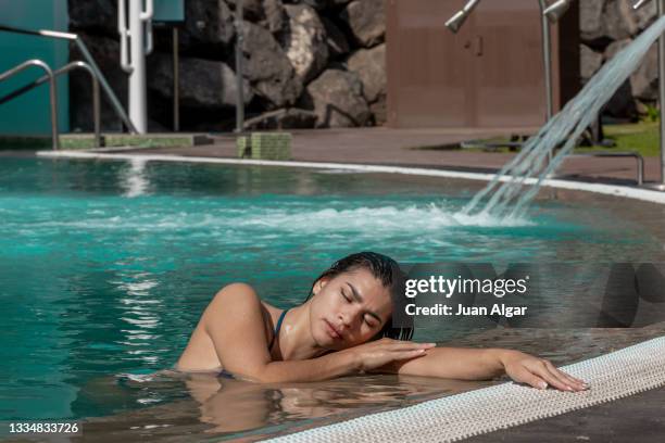 full lenght view of latina woman relaxing at the edge of the pool - algar waterfall spain stock pictures, royalty-free photos & images