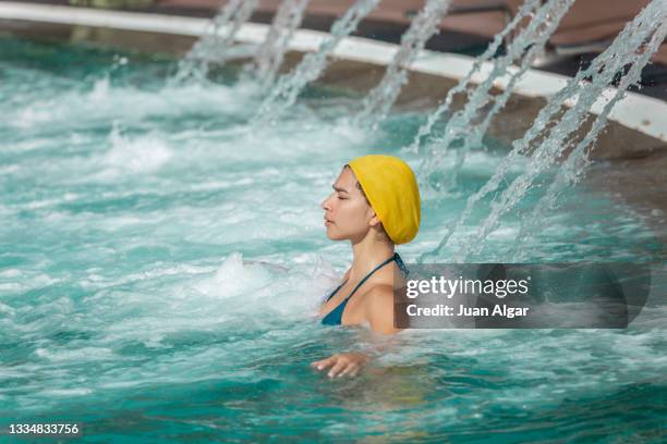 woman in hydrotherapy waterfall jet in swimming pool - algar waterfall spain stock pictures, royalty-free photos & images