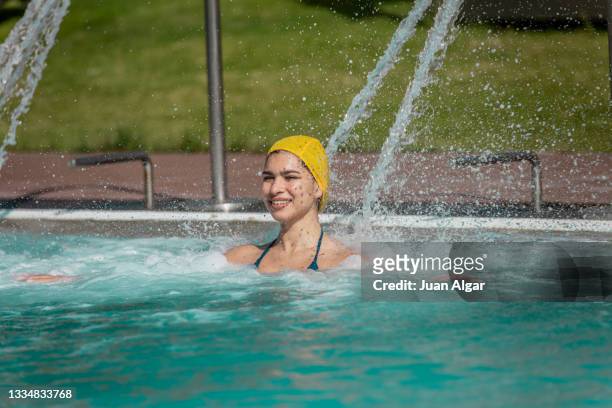 cheerful latina woman in hydrotherapy waterfall jet in swimming pool - algar waterfall spain stock pictures, royalty-free photos & images