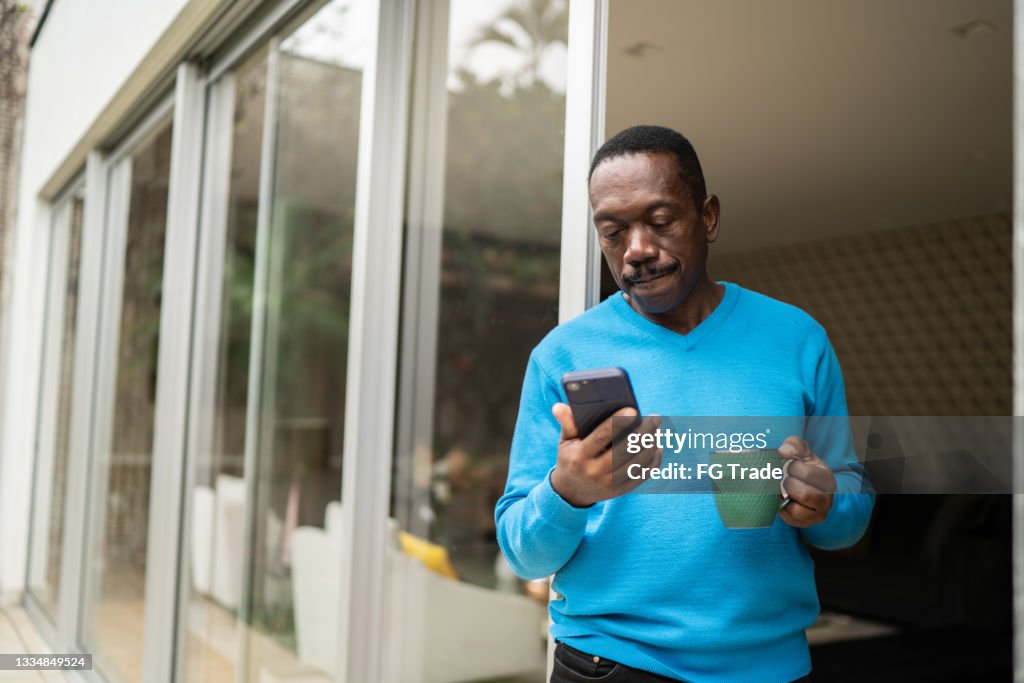 Senior man looking at smartphone at home