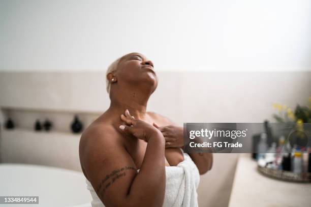 woman applying body mosture in the bathroom at home - voluptuous black women stockfoto's en -beelden