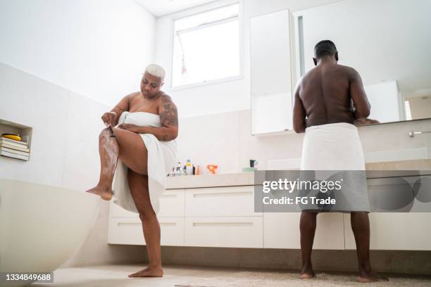 mature woman shaving her legs in the bathroom at home - lâmina de barbear imagens e fotografias de stock