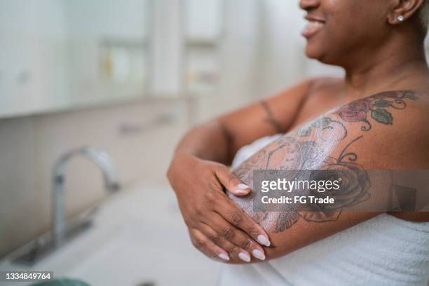 woman applying body mosture in the bathroom at home - tattoo 個照片及圖片檔
