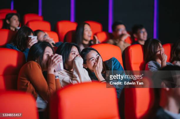 asian chinese  group of people watching horror scary movie in cinema movie theatre covering face - girlfriends films stockfoto's en -beelden