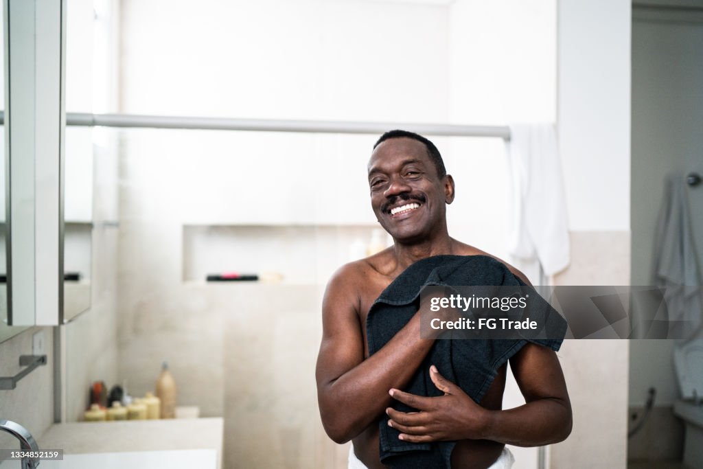 Portrait d’un homme âgé séchant avec une serviette dans la salle de bain à la maison