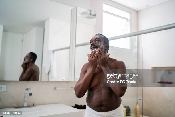 senior man applying facial mask at home - senior getting dressed stock pictures, royalty-free photos & images