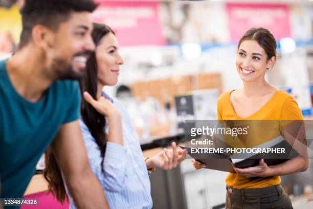 verkäuferin, die junges paar beim einkaufen unterstützt - verkäuferin stock-fotos und bilder
