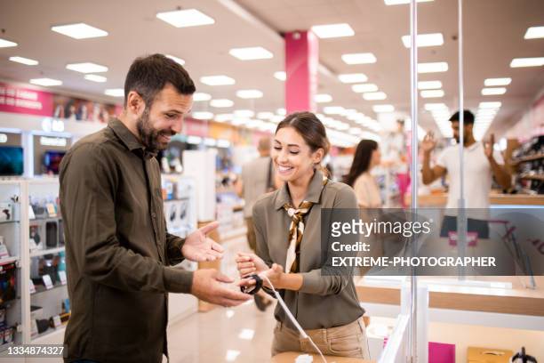 male customer receiving assistance from a saleswoman - tradeshow stock pictures, royalty-free photos & images
