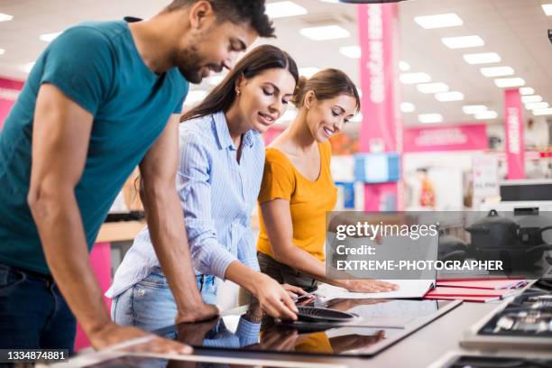 young couple receiving assistance from a saleswoman - hob stock pictures, royalty-free photos & images